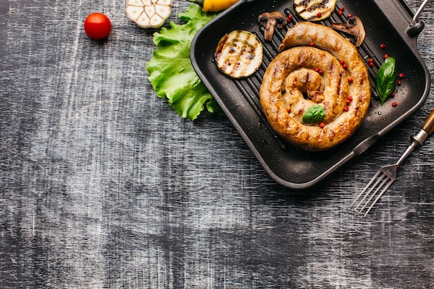 Вид сверху спираль на гриле колбаса с овощами в сковороде