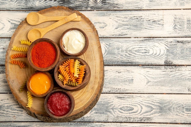 Pasta a spirale vista dall'alto con diversi condimenti sulla scrivania rustica grigia