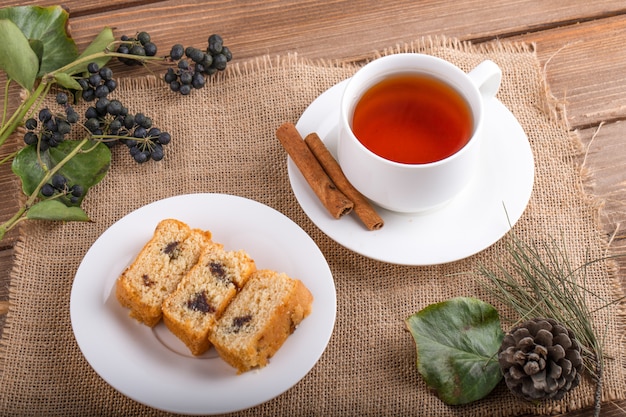 Top view of sponge cake slices on a plate with a cup of black tea on rustic background