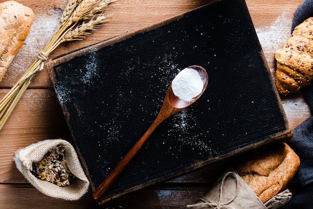 Top view of spoon with flour on wooden table