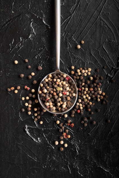 Foto gratuita cucchiaio vista dall'alto con grani di pepe