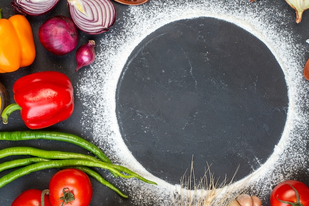 Top view sprinkled flour circle tomatoes red onions bell peppers green hot peppers on table free space