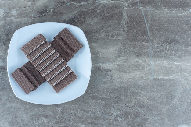 Top view of stack of chocolate wafers on white plate.