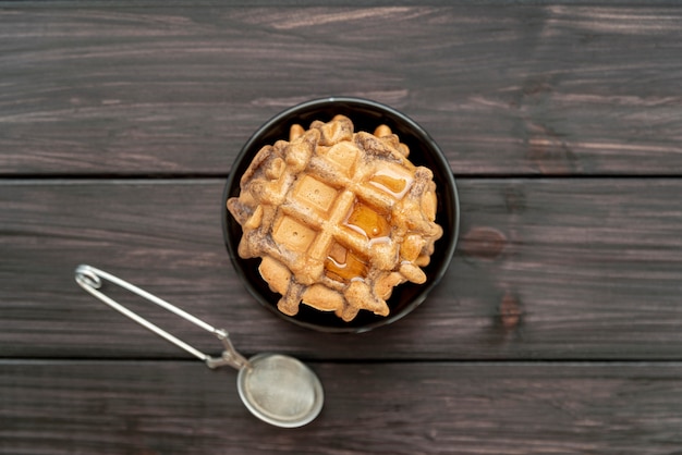 Free photo top view of stack of waffles on plate with honey and sieve