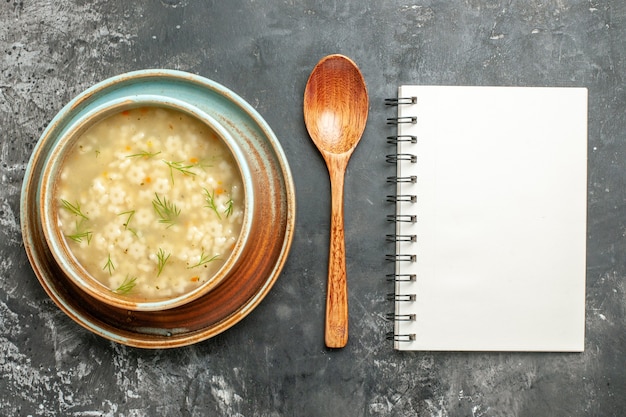 Top view star soup in bowl wooden spoon notepad on dark surface