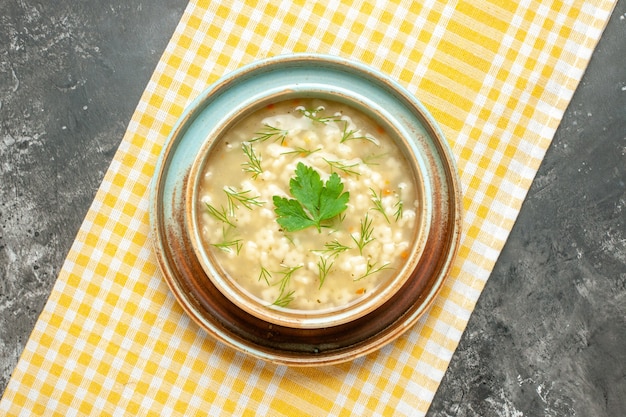 Free photo top view star soup in bowl on yellow tablecloth on dark background