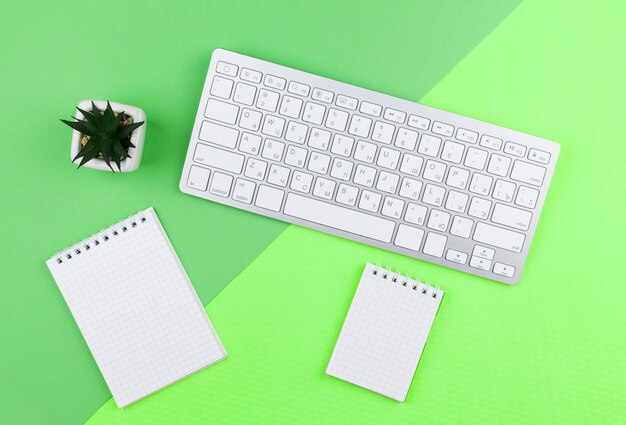 Top view stationery arrangement on green background with empty notepads 