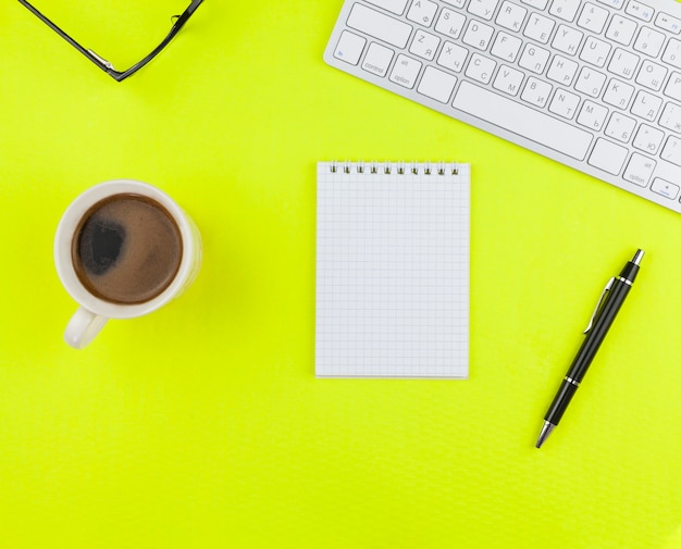 Top view stationery arrangement on yellow background