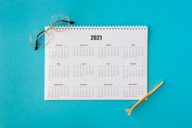 Top view stationery calendar with reading glasses