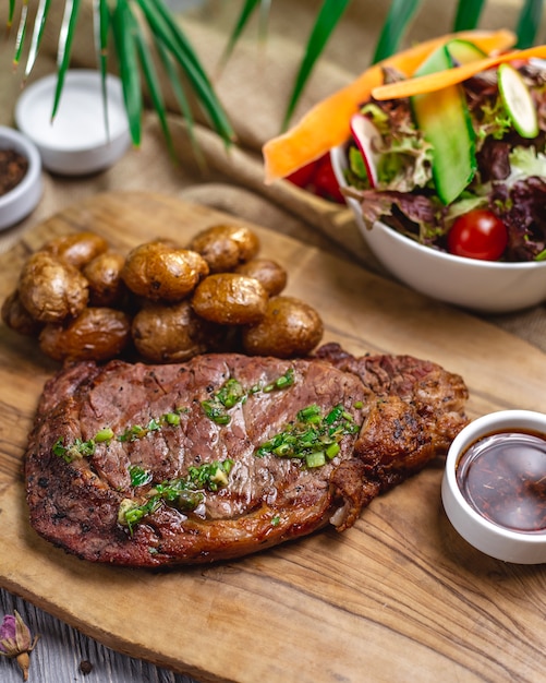 Top view steak with baked potatoes and vegetable salad