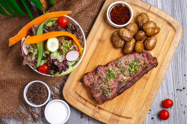 Top view steak with baked potatoes and vegetable salad