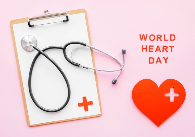 Free photo top view of stethoscope with notepad and paper heart