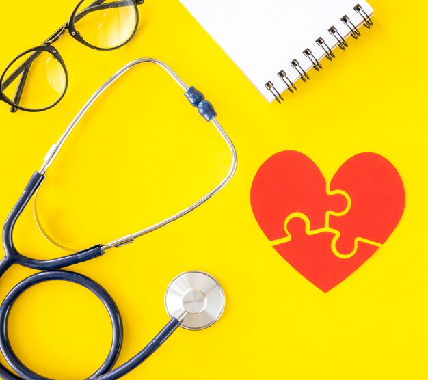 Top view of stethoscope with notepad and puzzle heart