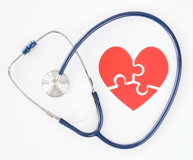 Free photo top view of stethoscope with puzzle paper heart