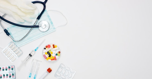 Top view of stethoscope with syringe and pills