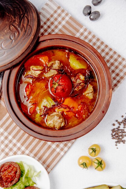 Top view of stewed meat with tomatoes and potatoes in a clay pot