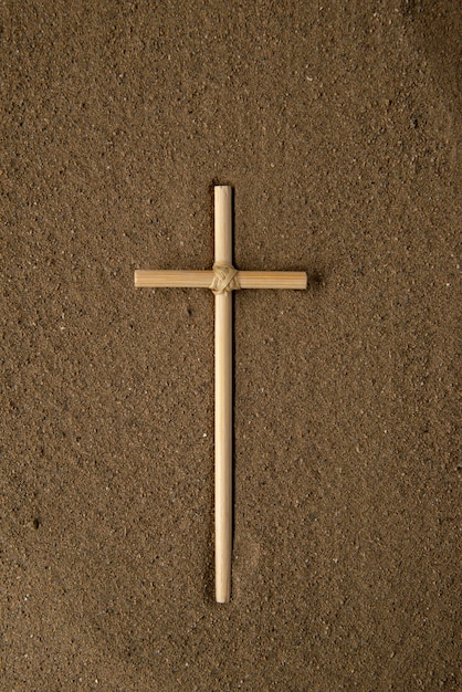 Вид сверху на палку-крест на коричневом песке