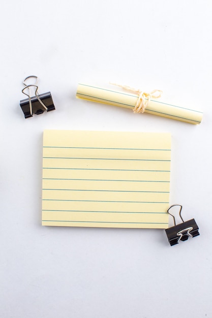 Top view sticky note binder clips rolled up paper tied with rope on white table