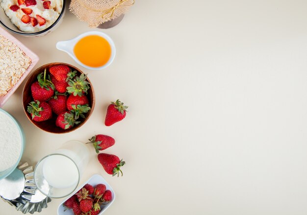 복사 공간 왼쪽 및 흰색 표면에 코티지 치즈 버터 우유 귀리와 그릇에 딸기의 상위 뷰