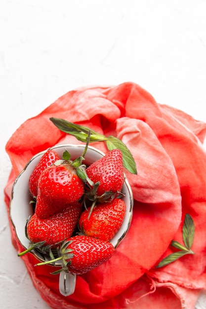 Free photo top view strawberries in coffee cup on red cloth on white background. vertical