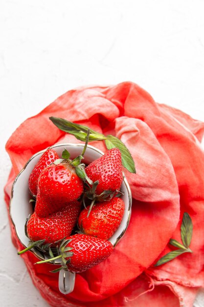 Top view strawberries in coffee cup on red cloth on white background. vertical