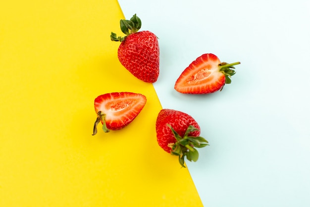 top view strawberries sliced whole juicy mellow on the yellow blue desk