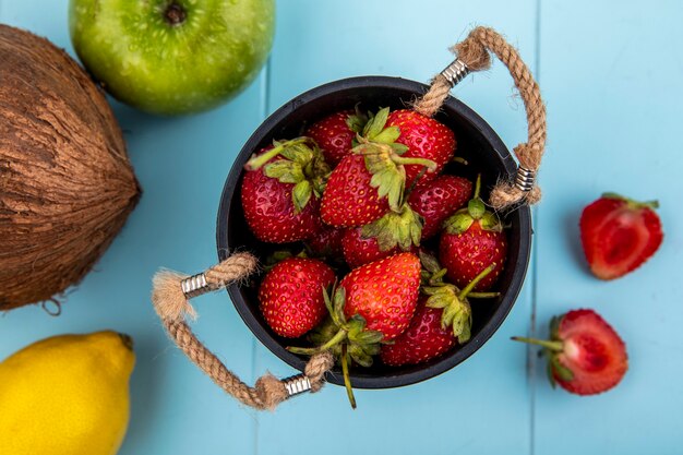 Top view of strawberry on a basket with slices of strawberry with coconut on a blue background