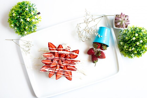 A top view strawberry cake with sliced fresh strawberries decorated with cream along with whole strawberries inside white desk fruit berry sugar