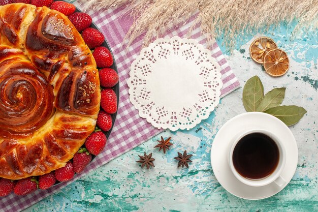 Top view strawberry pie with cup of tea on the blue surface