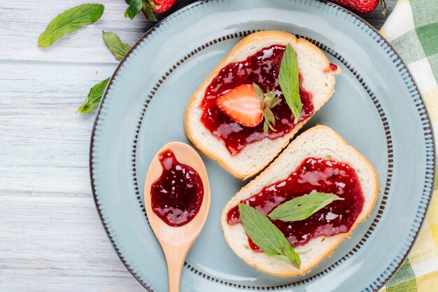 Foto gratuita vista superiore toast alla fragola pane bianco con marmellata di fragole e menta in cima