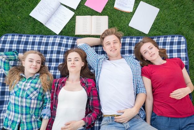 Foto gratuita vista superiore di studenti che si trovano sulla coperta da picnic