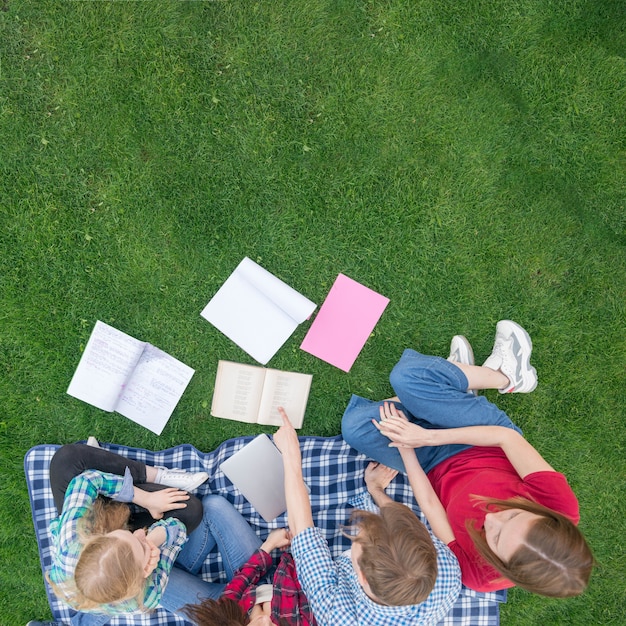 草の上の本を持つ学生のトップビュー