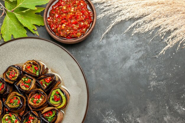 Top view stuffed aubergine rolls on white plate adjika on grey surface