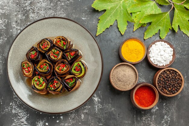 Top view stuffed eggplant rolls in white plate different spices plane tree leaves on grey surface