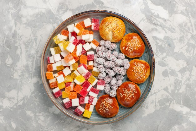 Top view sugar candies with little buns on white surface