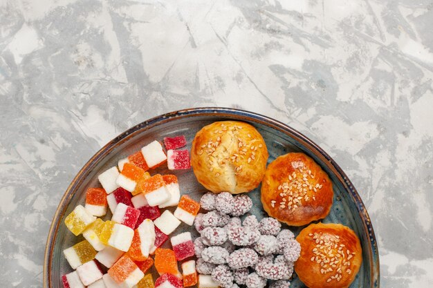 Top view sugar candies with little sweet buns on light-white surface