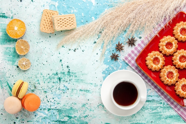 무료 사진 밝은 파란색 배경에 차와 마카롱 컵과 빨간 접시 안에 상위 뷰 설탕 쿠키