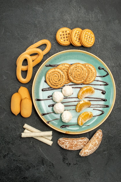 Top view sugar cookies with biscuits and candies on grey background