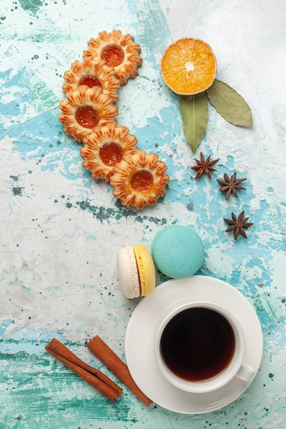 Вид сверху сахарного печенья с макаронами и чашкой чая на синей поверхности