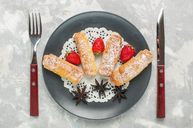 Top view of sugar powdered bagels delicious dough with fresh strawberries on white surface