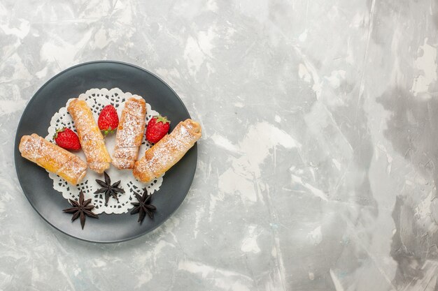 흰색 표면에 딸기와 설탕 가루 베이글 맛있는 반죽의 상위 뷰