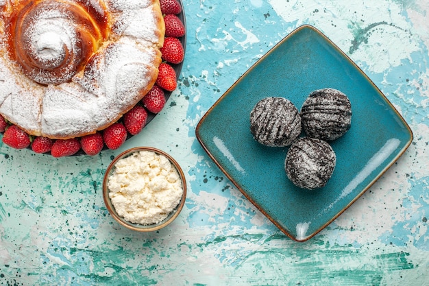 Foto gratuita torta di zucchero a velo vista dall'alto con fragole fresche e torte al cioccolato sulla superficie blu