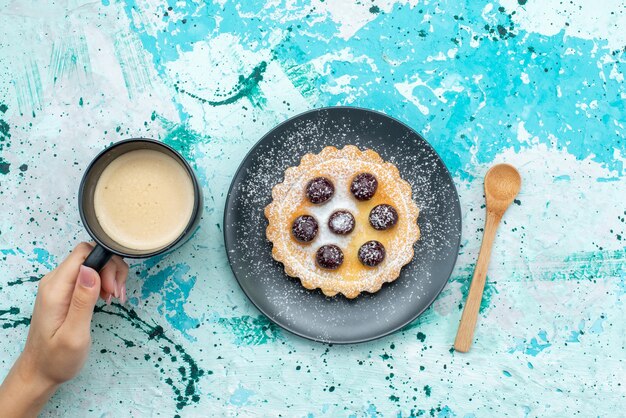 青い机の上の牛乳と一緒に果物と砂糖粉末ケーキの上面図砂糖ビスケットカラー写真