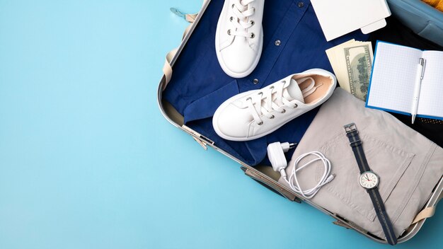 Вид сверху на чемодан для путешествий с одеждой и часами