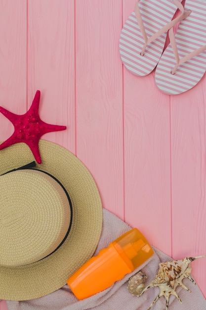 Top view of summer elements on pink wooden surface