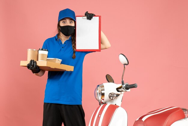 Top view of surprised courier girl wearing medical mask gloves standing next to motorcycle