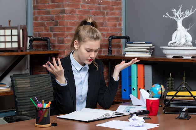 Top view of surprised lady sitting at a table and focused on something carefully in the office