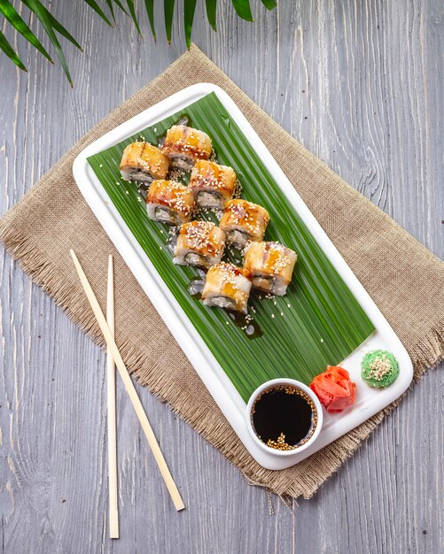 Top view sushi rolls with eel with ginger wasabi and soy sauce on a plate