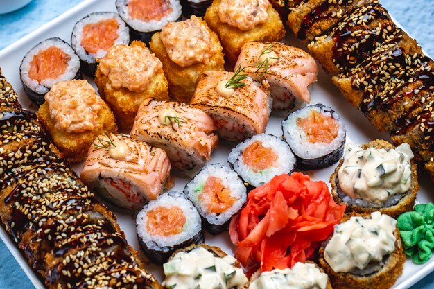 Top view sushi set hot sushi roll with teriyaki sauce and sesame seeds philadelphia wit salmon sake maki wasabi and ginger on a board
