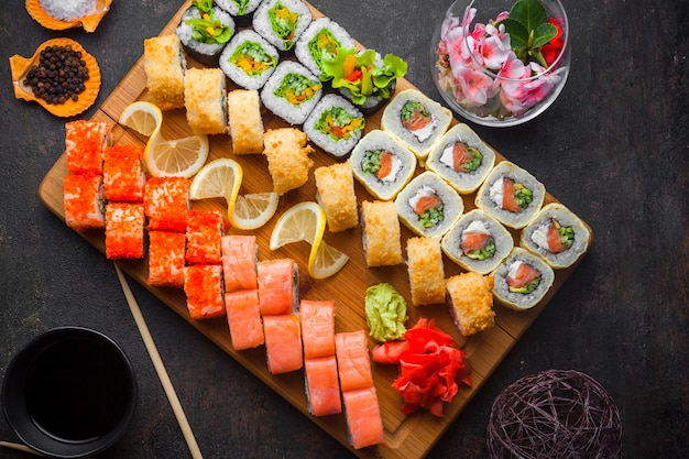 Top view sushi set with soy sauce and chopsticks in wooden serving board